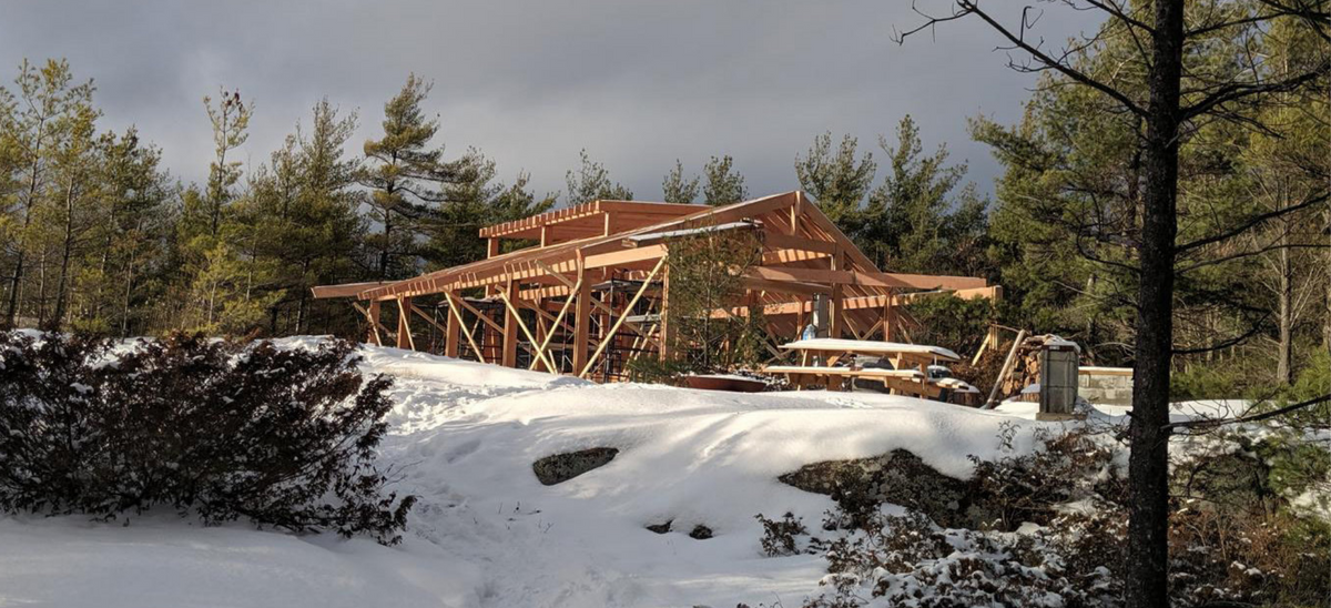 Wooden structure under construction in a snowy forest setting