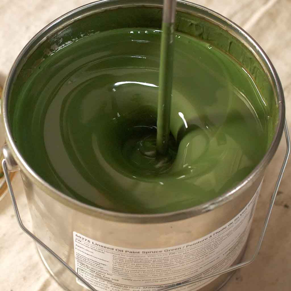 Green paint being mixed with a drill operated paint mixer.