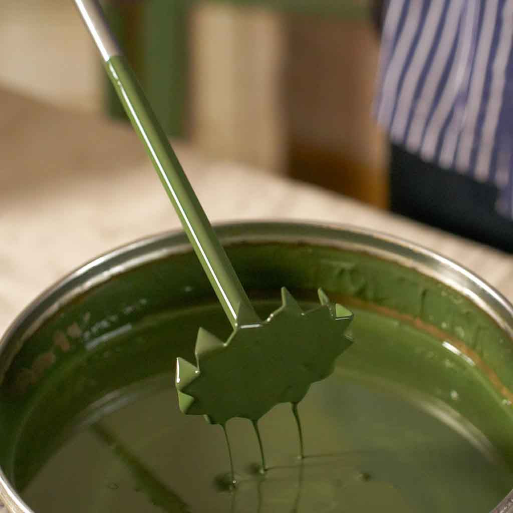 Green paint being mixed with a drill operated paint mixer.