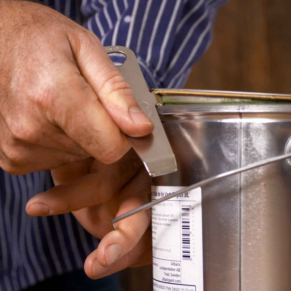 Person using the Allbäck Paint Can Opener on a 3 L metal paint can with rubber gasket.