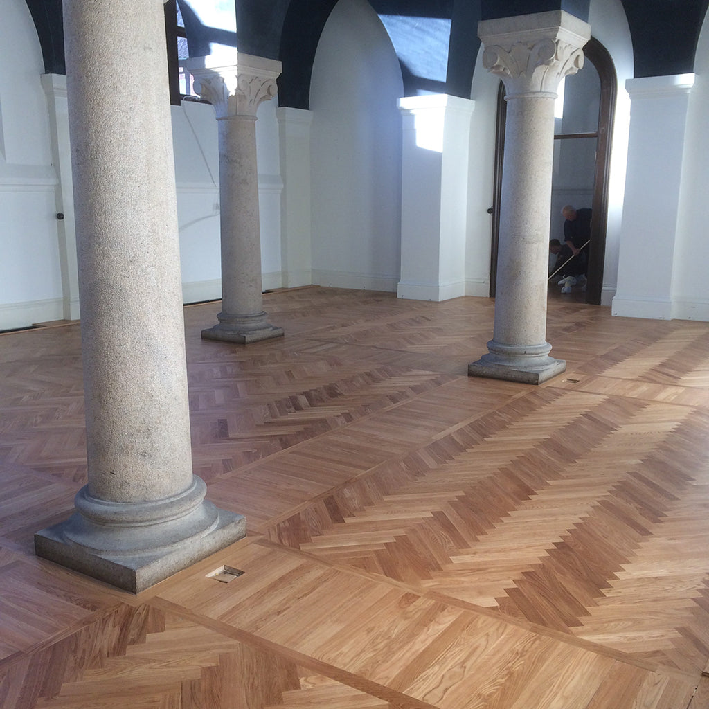 A room with stone columns and an oak floor, laid in a herringbone pattern, in Pelarsalen, a hall at Lund University, Sweden.