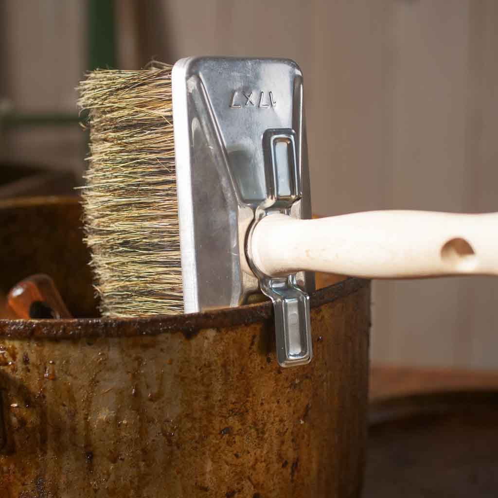 Metal brush with bristles in a rusty metal container