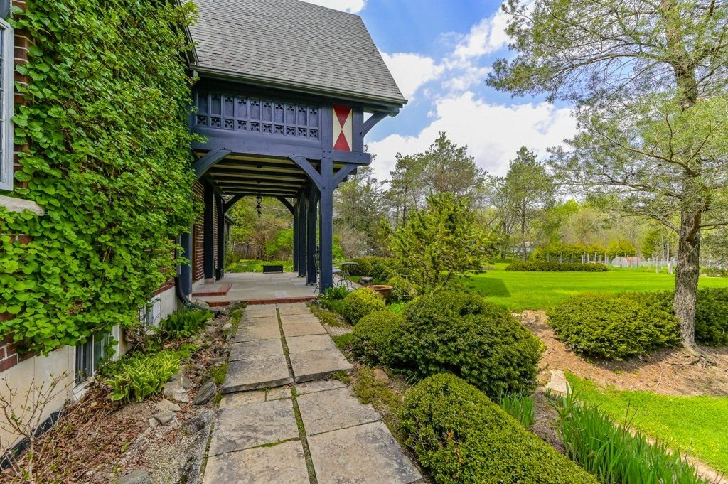 Timber porch wrapped in climbing vines beside a stone path