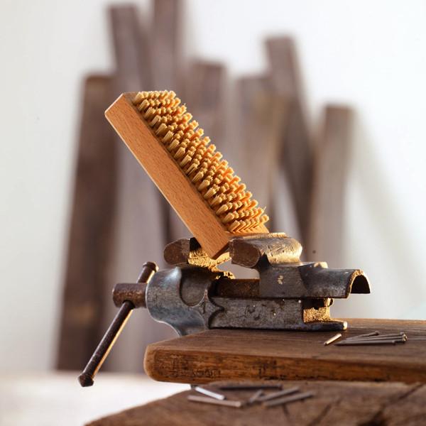 Nail Brush standing in metal vice that is secured to a work bench