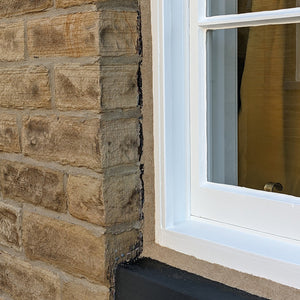 Traditional sash window set in limestone opening and sealed with Sand Mastic.