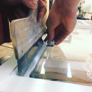 Using Scandinavian WindowCraft Ergo Glass Scraper to trim linseed oil paint lines from glass during window restoration.