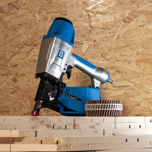 LIGNOLOC® F44 Pneumatic Coil Nailer and a coil of LIGNOLOC® F44 Wooden Nails, Ø 3.7 mm shown together on a stack of structural wood panelling with an OSB background.