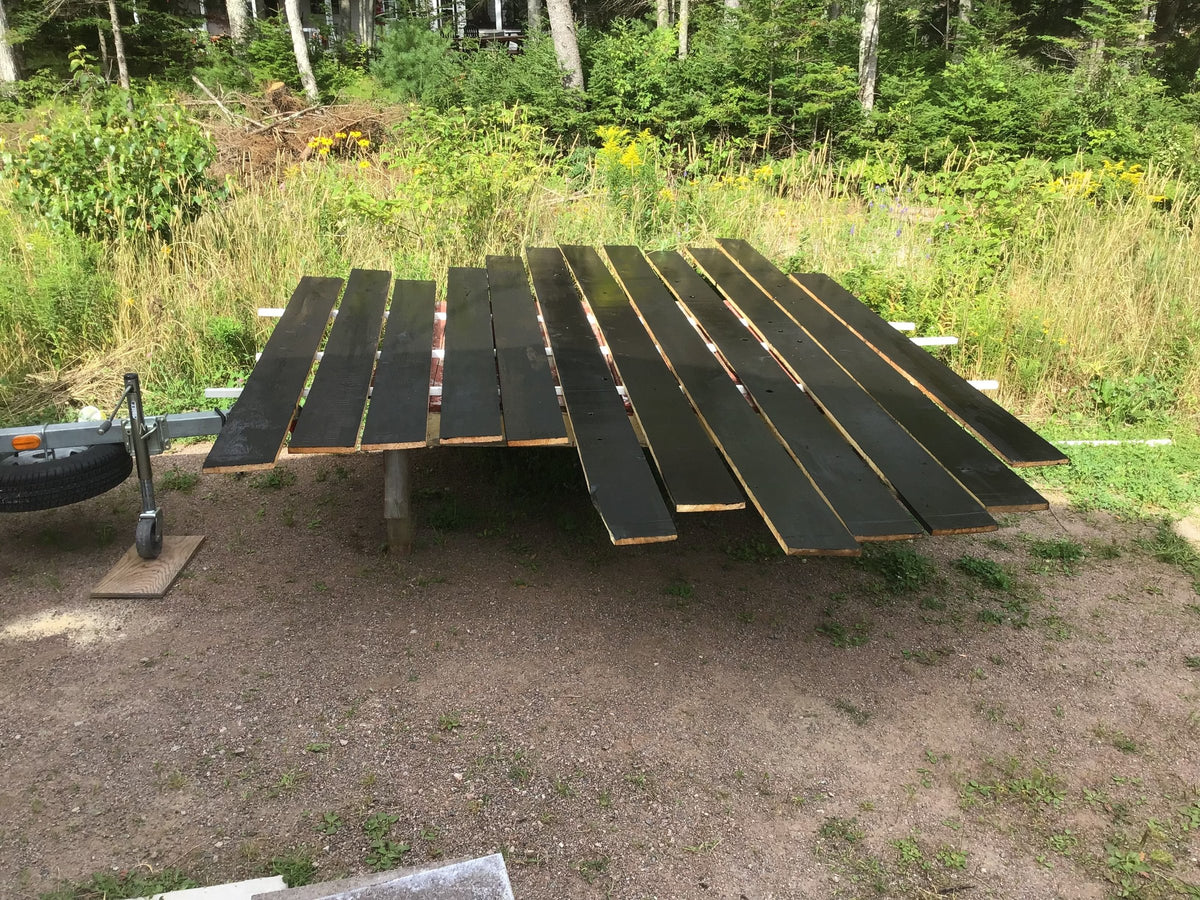 Painted planks drying on sawhorses outdoors
