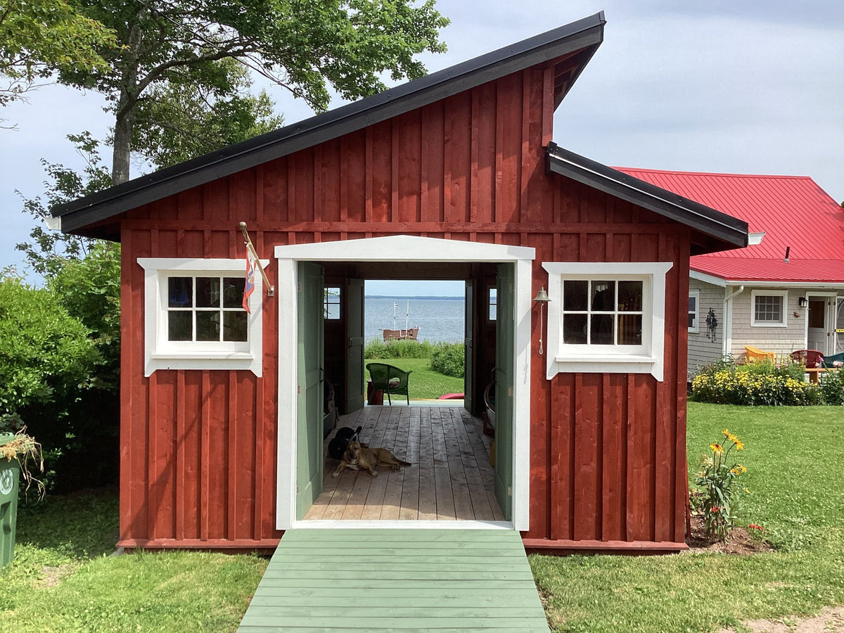 Red pine tar boat shed with white trim and open doors facing the water